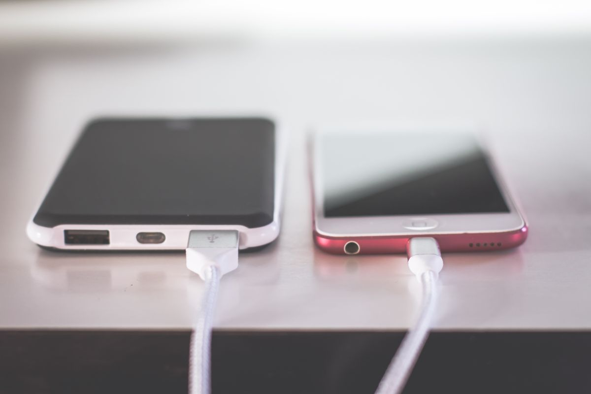 A portable power bank charging a smartphone on a desk